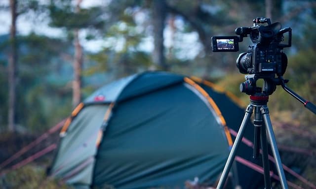 Kamera på stativ peker mot et telt i skogen i bakgrunnen