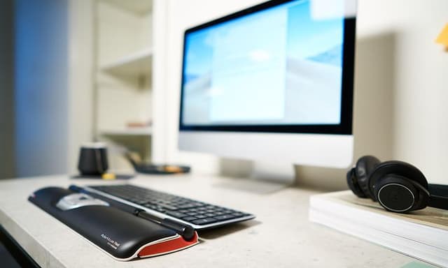 Contour RollerMouse på ett skrivbord bredvid en datorskärm och headset